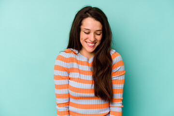 Obraz premium Young caucasian woman isolated on blue background laughs and closes eyes, feels relaxed and happy.