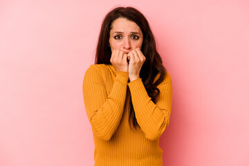 Young caucasian woman isolated on pink background biting fingernails, nervous and very anxious.