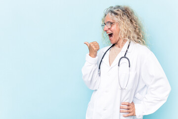 Middle age caucasian woman isolated on blue background points with thumb finger away, laughing and carefree.