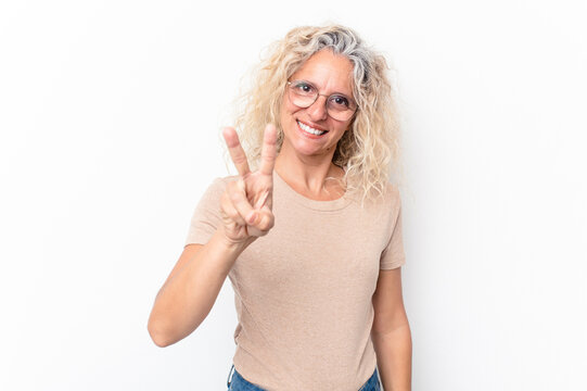 Middle age caucasian woman isolated on white background showing victory sign and smiling broadly.