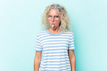 Middle age caucasian woman isolated on blue background funny and friendly sticking out tongue.