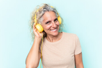 Middle age caucasian woman listening to music isolated on blue background