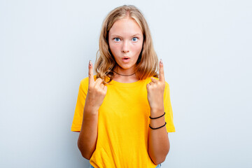 Obraz premium Caucasian teen girl isolated on blue background pointing upside with opened mouth.