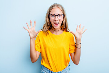 Caucasian teen girl isolated on blue background receiving a pleasant surprise, excited and raising hands.