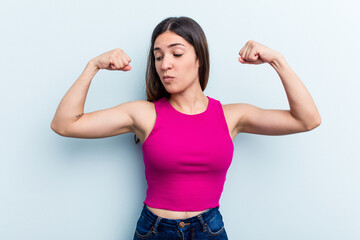 Young caucasian woman isolated on blue background showing strength gesture with arms, symbol of feminine power