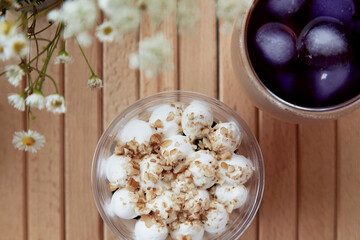 Vegan gluten free light nuts dessert in a disposable cup. Cold cocktail with anchan blue tea, antioxidants at the terrace, chamomile flowers outside..