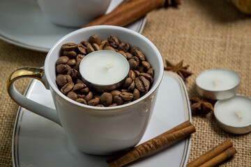 Tea candle in a cup with coffee beans. Aromatic tea candle.