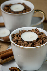 Tea candle in a cup with coffee beans. Aromatic tea candle.