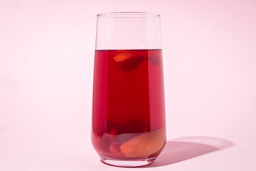 A glass of apple compote on a pink background. Fruit drink.