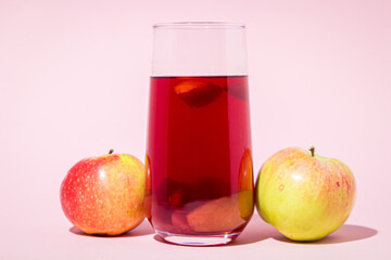 A glass of apple compote on a pink background. Fruit drink.