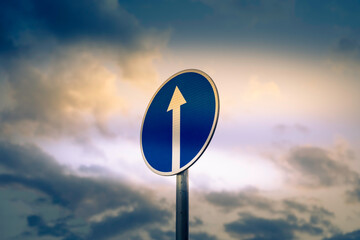 Road sign on the background of the sky with clouds