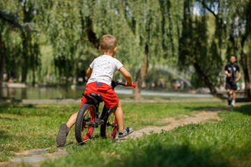 little boy riding a bike in a city park