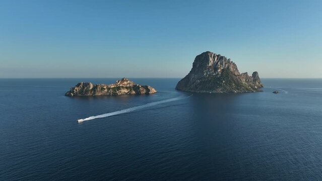 Aerial video of Es Vedra and Es Vedranell islands in Ibiza, yacht returning from visiting it sailing the sea.