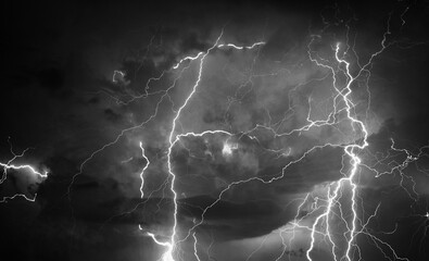 Fork lightning striking down during summer storm in black and white