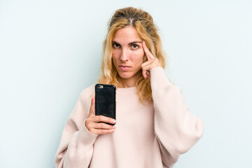 Fototapeta premium Young caucasian woman holding mobile phone isolated on blue background pointing temple with finger, thinking, focused on a task.