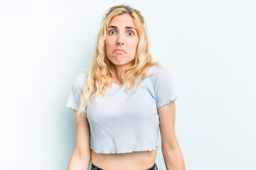 Naklejka premium Young caucasian woman isolated on blue background shrugs shoulders and open eyes confused.
