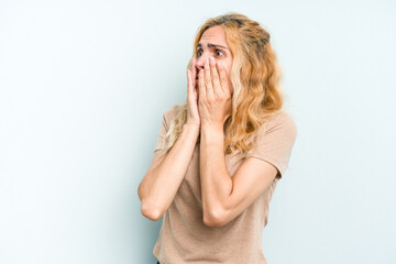 Young caucasian woman isolated on blue background scared and afraid.