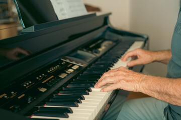 Old person's hands playing the piano. Close up view of skin texture and piano keys.