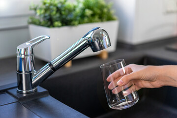 Filling a glass with drinking water from the kitchen faucet