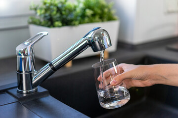 Woman hands filling a glass of tap water