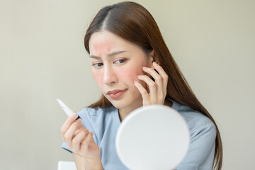 Dermatology, asian young woman looking at mirror, holding cream tube in hand, expression worry and...