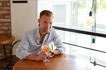 portrait of an attractive man with a cocktail on the table