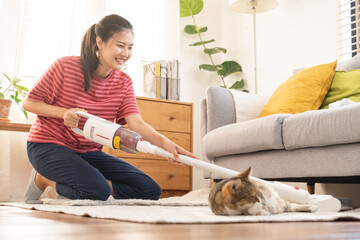 Happy asian young housekeeper woman using vacuum cleaning, cleaner to remove dust, hair or fur on...