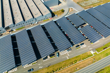 Aerial view of solar panels installed over parking lot with parked cars for effective generation of...