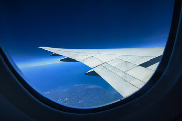 View of the world and clouds from the window of an airplane flying in the sky.