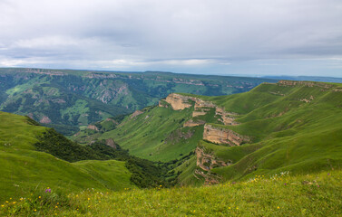 Panoramic view of green mountains and hills from the Bermamyt plateau in Karachay-Cherkessia in Russia on a cloudy summer day and a space for copying