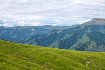 Beautiful landscape - panoramic view of green mountains and hills blurred in morning haze from bermamyt plateau in karachay-cherkessia Russia and dramatic clouds and copy space