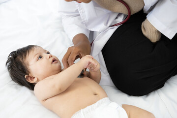 doctor pediatrician examining infant baby on the bed