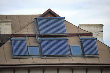 Fototapeta premium Building roof with rows of vacuum air solar collectors for water heating and producing of clean ecological energy. Renewable heat energy with zero emission
