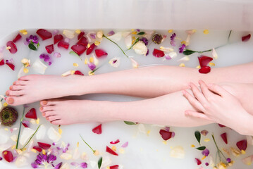 Obraz na płótnie Canvas female legs in flowers and milk