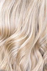 Hair coloring women close up texture background. Bunch of shiny straight blond hair in a wavy curved style. Copy space.