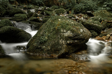 Naklejka na ściany i meble Big stone - stream water in the mountains - start of the big river