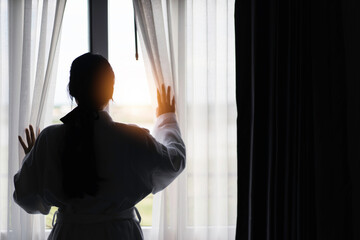 women standing with curtains on window