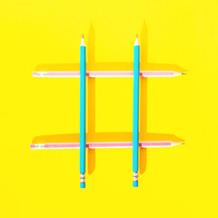 Four wooden pencils on yellow background assembled in a shape of hashtag. Top view, flat lay. School concept. Social media or marketing idea creative concept. Contemporary business artistic design.