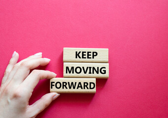 Keep moving forward symbol. Concept words keep moving forward on wooden blocks. Beautiful red background. Businessman hand. Business and keep moving forward concept. Copy space.
