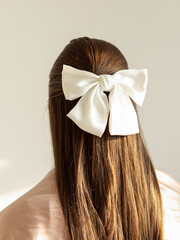 White hairpin-bow made of silk. Accessory for the bride. Hairpin on dark hair. Natural