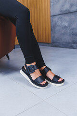 Women's legs close-up in black leather sandals made of genuine leather.Collection of women's summer shoes