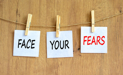 Face your fears and support symbol. Concept words Face your fears on white papers on wooden...