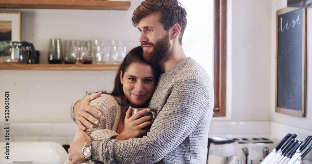 Wall mural Happy, smiling and loving couple enjoying coffee and a hug together in their kitchen. Young, romantic and affectionate caucasian adults in their new home. Husband and wife in their apartment bonding.