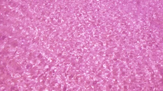 Amazing pink sea sand. Streams of water are flowing over the bright pink sand creating beautiful patterns of light and glare.