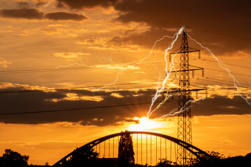 Golden sky with sun rays and lens flare shows solar energy with electricity tower pylon silhouette...