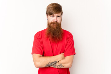 Young caucasian red-haired man isolated on white background frowning face in displeasure, keeps arms folded.