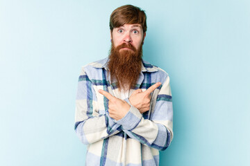 Young caucasian red-haired man isolated on blue background points sideways, is trying to choose between two options.