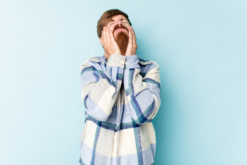 Young caucasian red-haired man isolated on blue background crying, unhappy with something, agony and confusion concept.