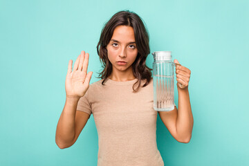 Young hispanic woman holding a water of jar isolated on blue background standing with outstretched hand showing stop sign, preventing you.