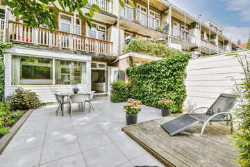 Neat paved patio with sitting area and small garden near wooden fence